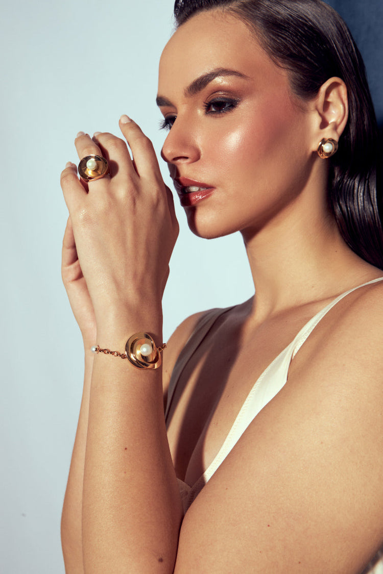 Mulher com semijoias elegantes em pérolas, brincos, anel e pulseira, em design clássico e moderno, em ouro 18k e 24k, antialérgicas.