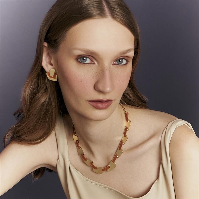 Mulher usando brincos e colar de semijoias em ouro, destacando-se pela alta qualidade e material antialérgico em 18k e 24k.