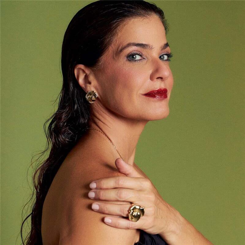 Mulher usando brinco dourado com design floral e zircônias, semijoias antialérgicas em ouro 18k vistas de lado.