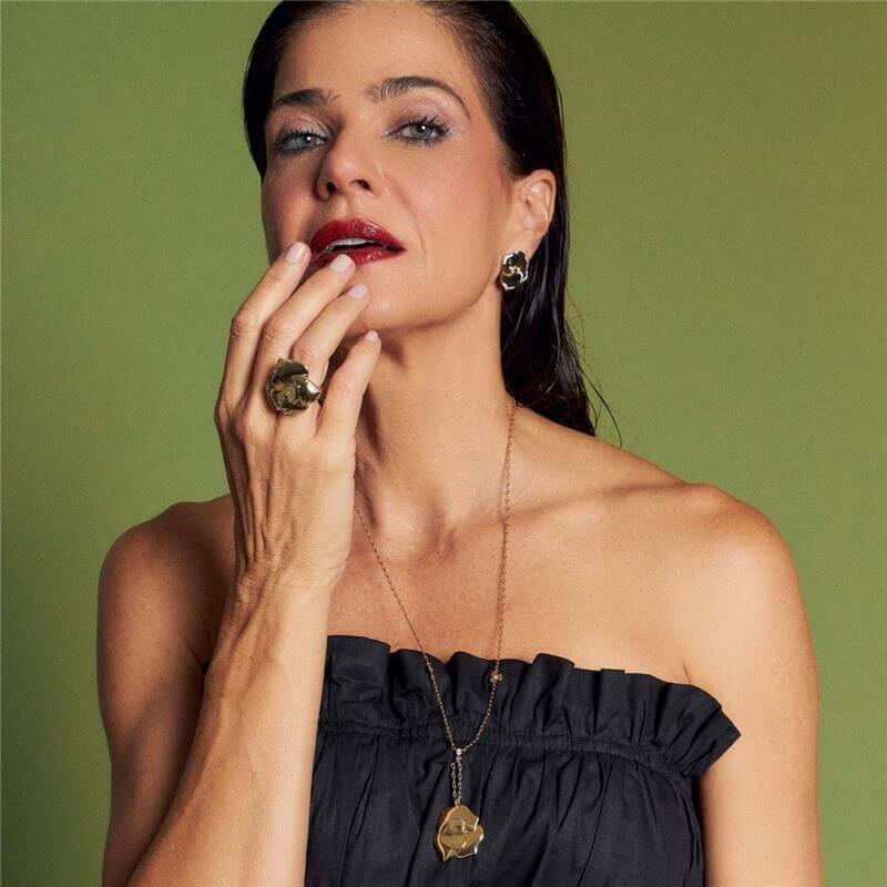 Mulher usando Colar Vera banhado a ouro 18k, semijoia antialérgica, destacando acabamento liso, peso de 12,20g, em fundo verde.