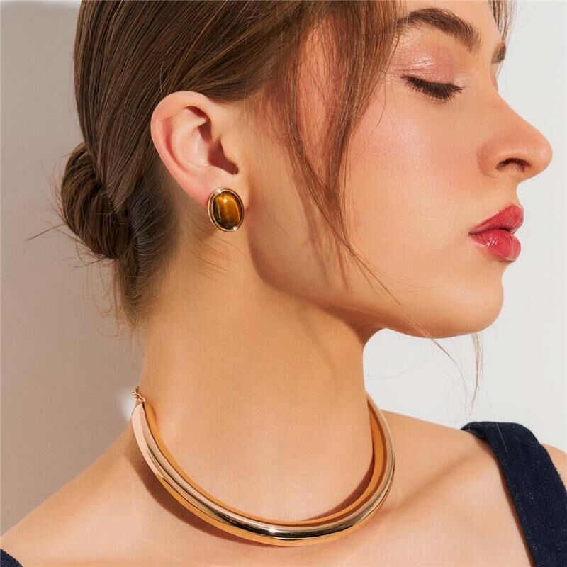 Mulher usando semijoias antialérgicas de alta qualidade, brinco dourado com cristal e colar elegante. Brinco Carmel, joias 18k e 24k.
