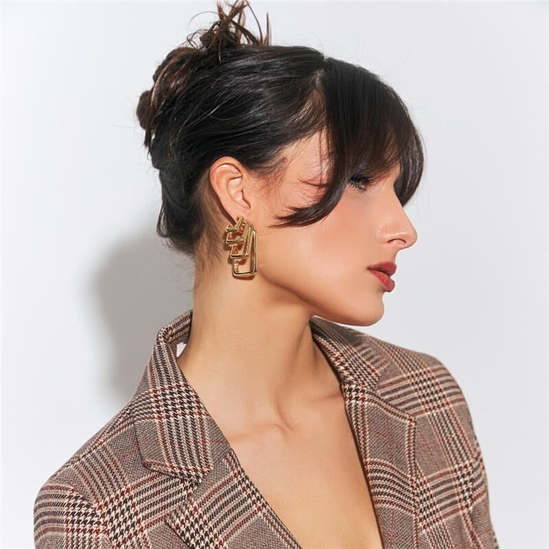Mulher usando argola Quattro dourada com zircônia e cristal, semijoia de alta qualidade com material antialérgico em 18k e 24k.