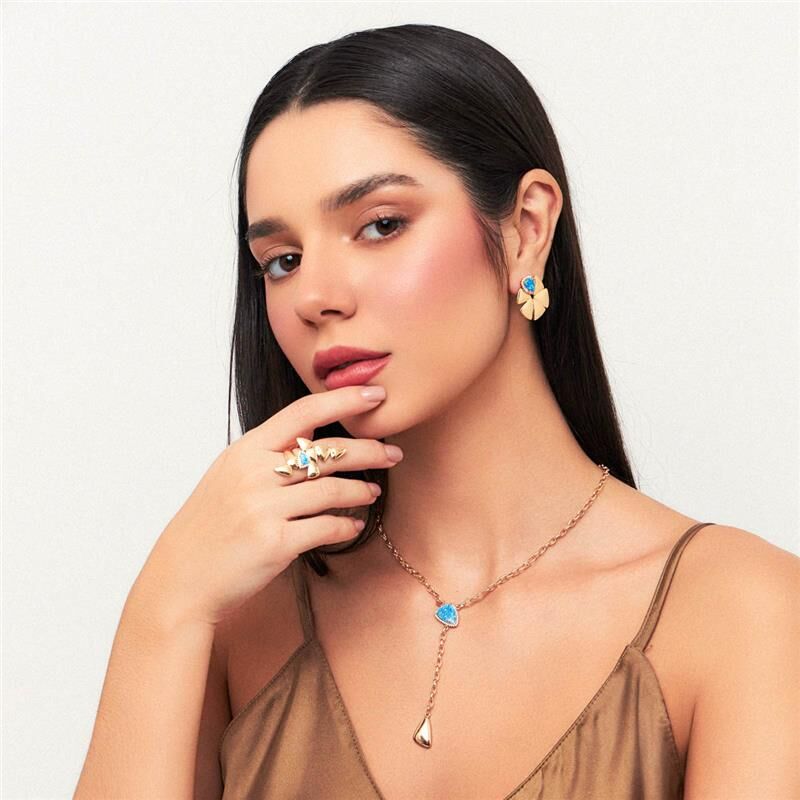 Mulher usando brincos e colar de cristal dourado, semijoias antialérgicas 18k, destacando design elegante e sofisticado.