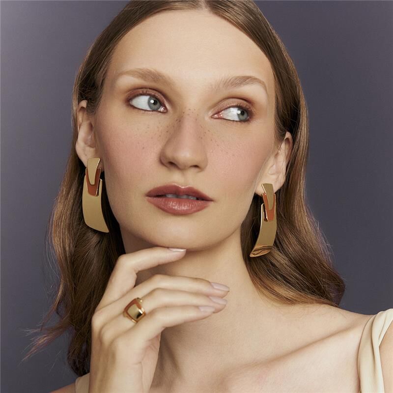 Mulher elegante usando Brinco Terracota Retangular, semijoia antialérgica em 18k, destacando seu design moderno e acabamento dourado.