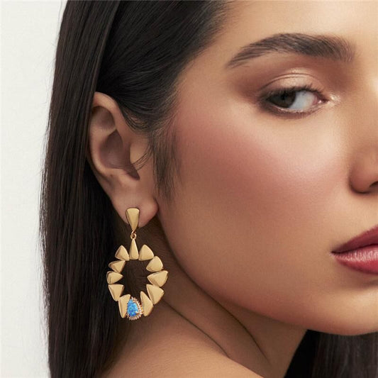 Mulher usando brinco Zuri Triad dourado com cristal e zircônia, semijoia antialérgica 18k e 24k de alta qualidade.