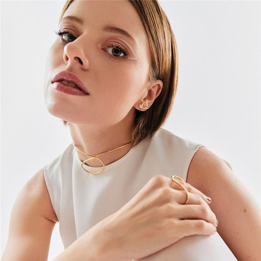Mulher elegante usando brinco ear cuff Moov, semijoia antialérgica em 18k, destacando-se em look clássico com acessórios dourados.