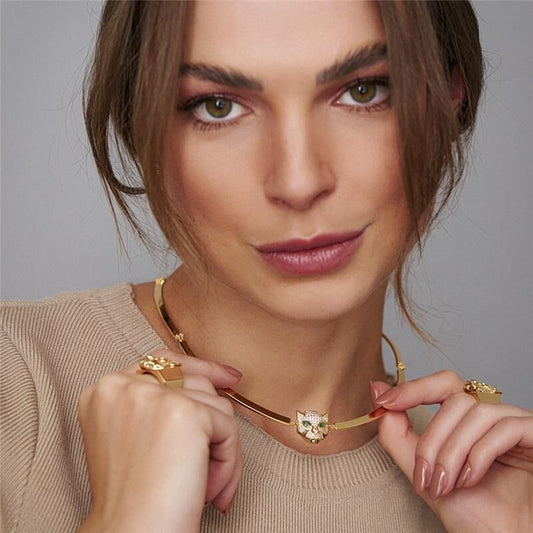 Mulher usando choker Leo dourada com zircônia, tamanho 35cm. Semijoias antialérgicas com pingente de 1.7cm x 1.5cm.