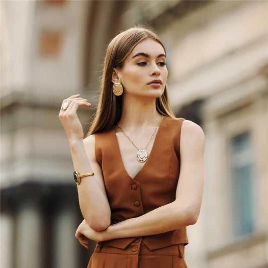 Mulher usando conjunto de semijoias antialérgicas em 18k e 24k, incluindo Brinco Solene com acabamento liso, banho dourado e ródio.