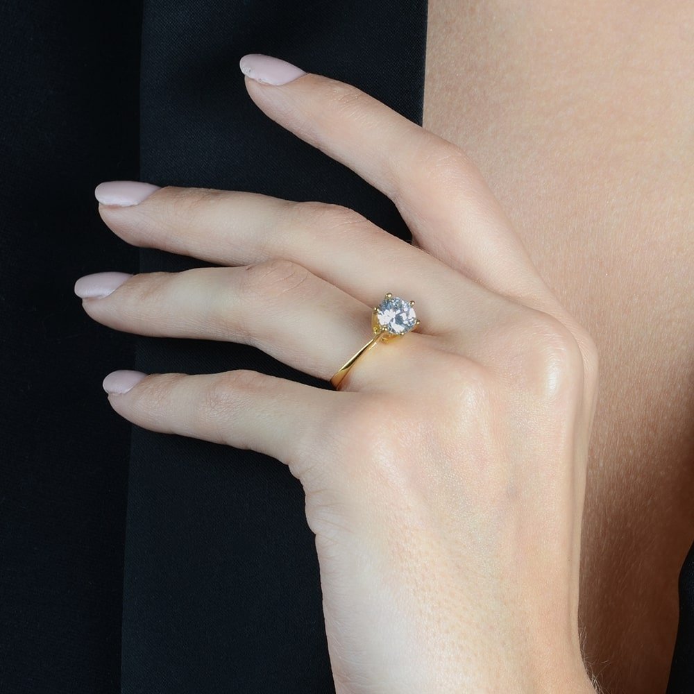 Anel de ouro 24k com zircônia G, semijoia antialérgica de alta qualidade no dedo de uma modelo elegante.