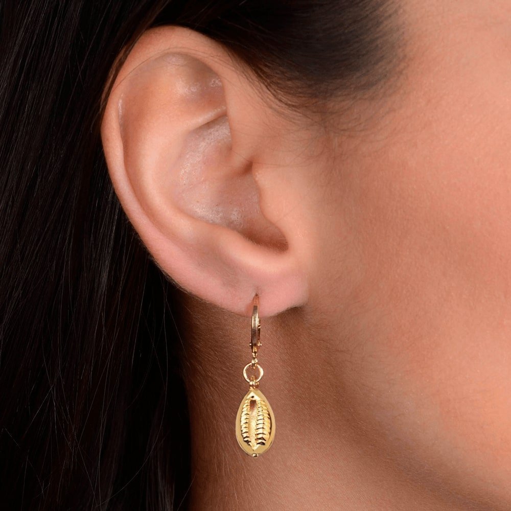 Mulher usando brinco dourado de argolinha com búzios, semijoias de alta qualidade em 24k, antialérgico e elegante.
