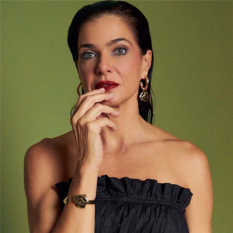 Mulher usando brinco de argola dourado, semijoia antialérgica em ouro 18k e 24k, acabamento liso.
