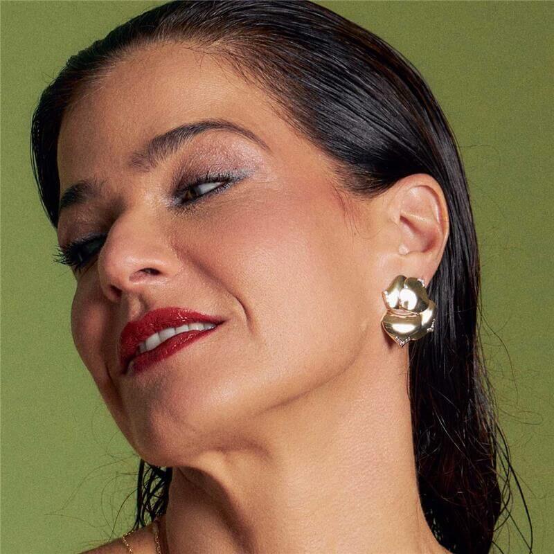 Mulher usando brinco Vera Ear Jacket Flor, uma semijoia antialérgica dourada em ouro 18k com pedra zircônia, destacando elegância.